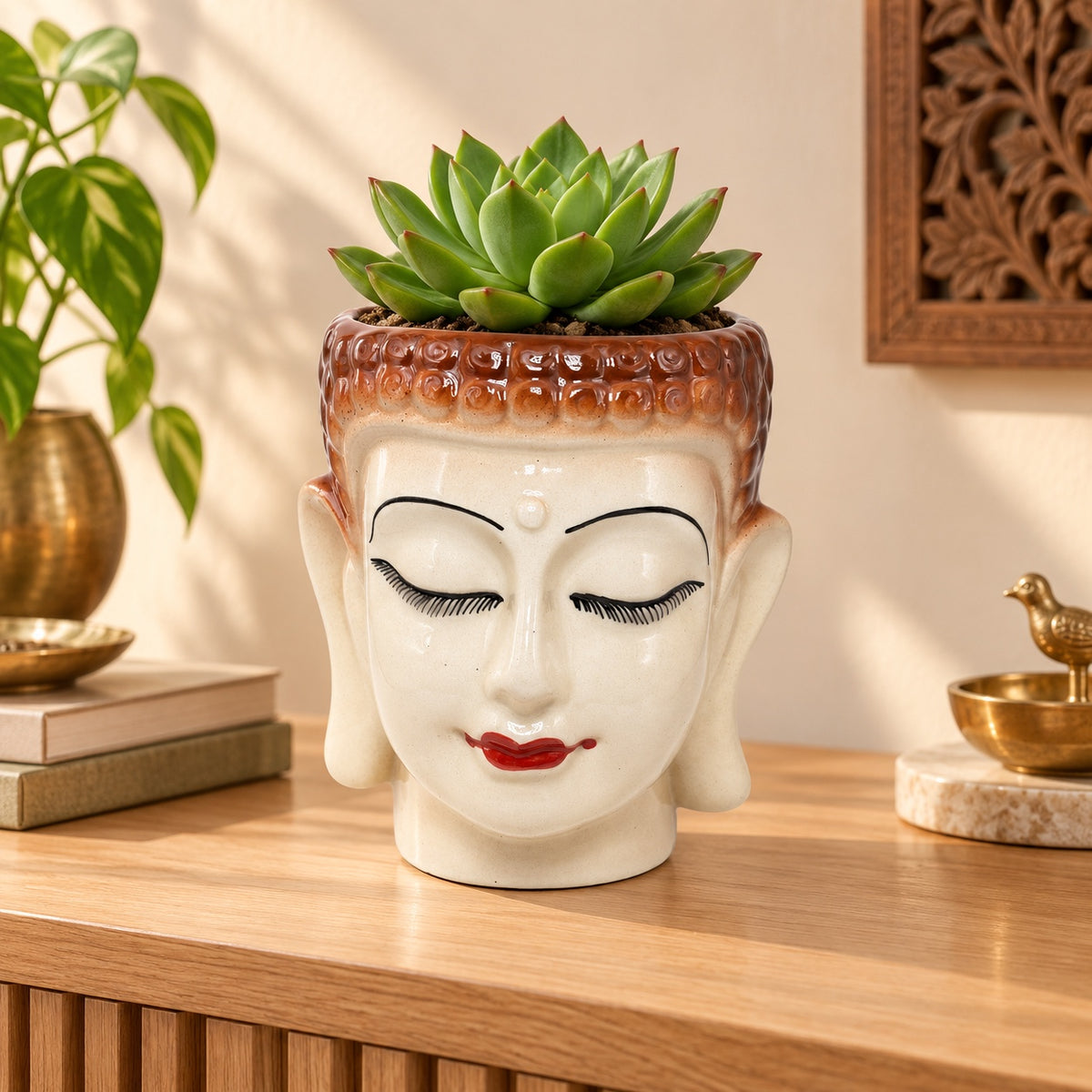 Large Buddha face ceramic planter styled with a succulent on a wooden console