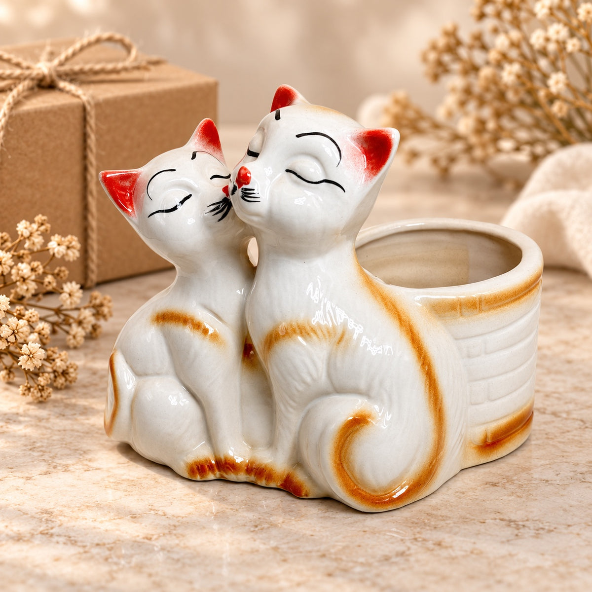 Kissing cats ceramic indoor planter styled as warm neutral home decor beside a gift box