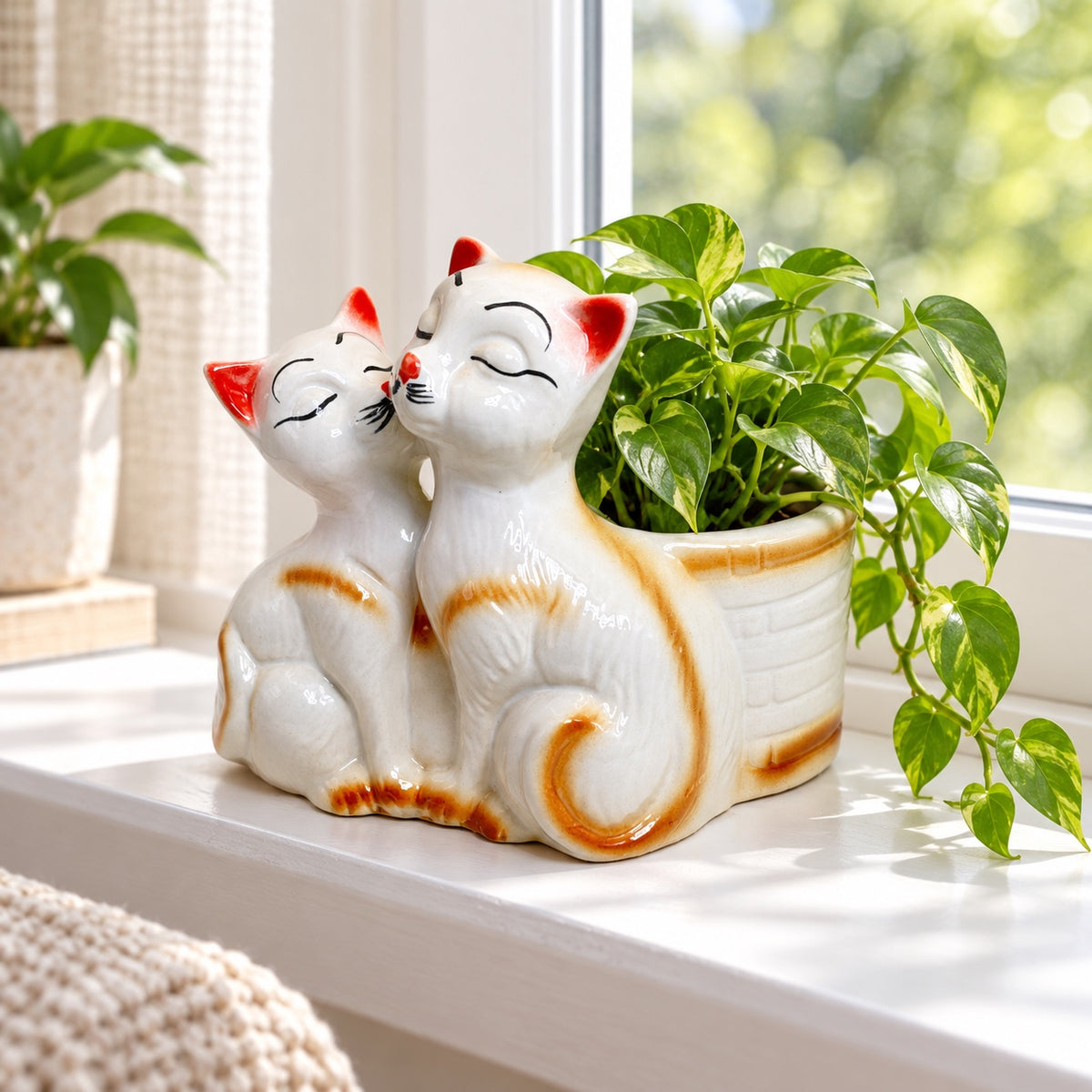 Kissing cats ceramic indoor planter styled with a pothos plant by a bright window